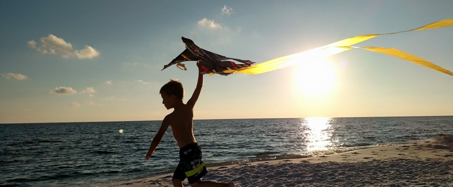 A child flies a kite at sunset.